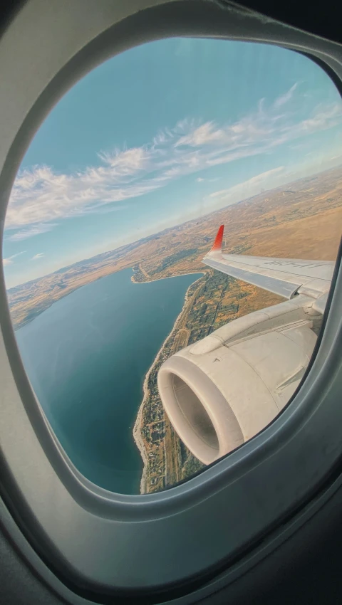 an airplane wing with a view of a lake and sky