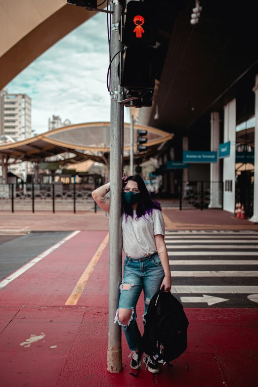 girl standing near cross walk with a backpack and luggage under her shoulder