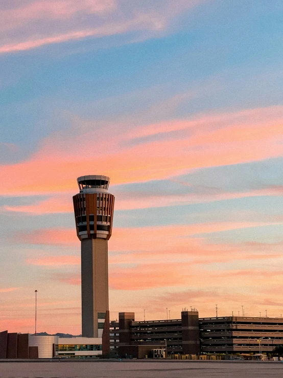 a plane flying by a control tower in the sunset