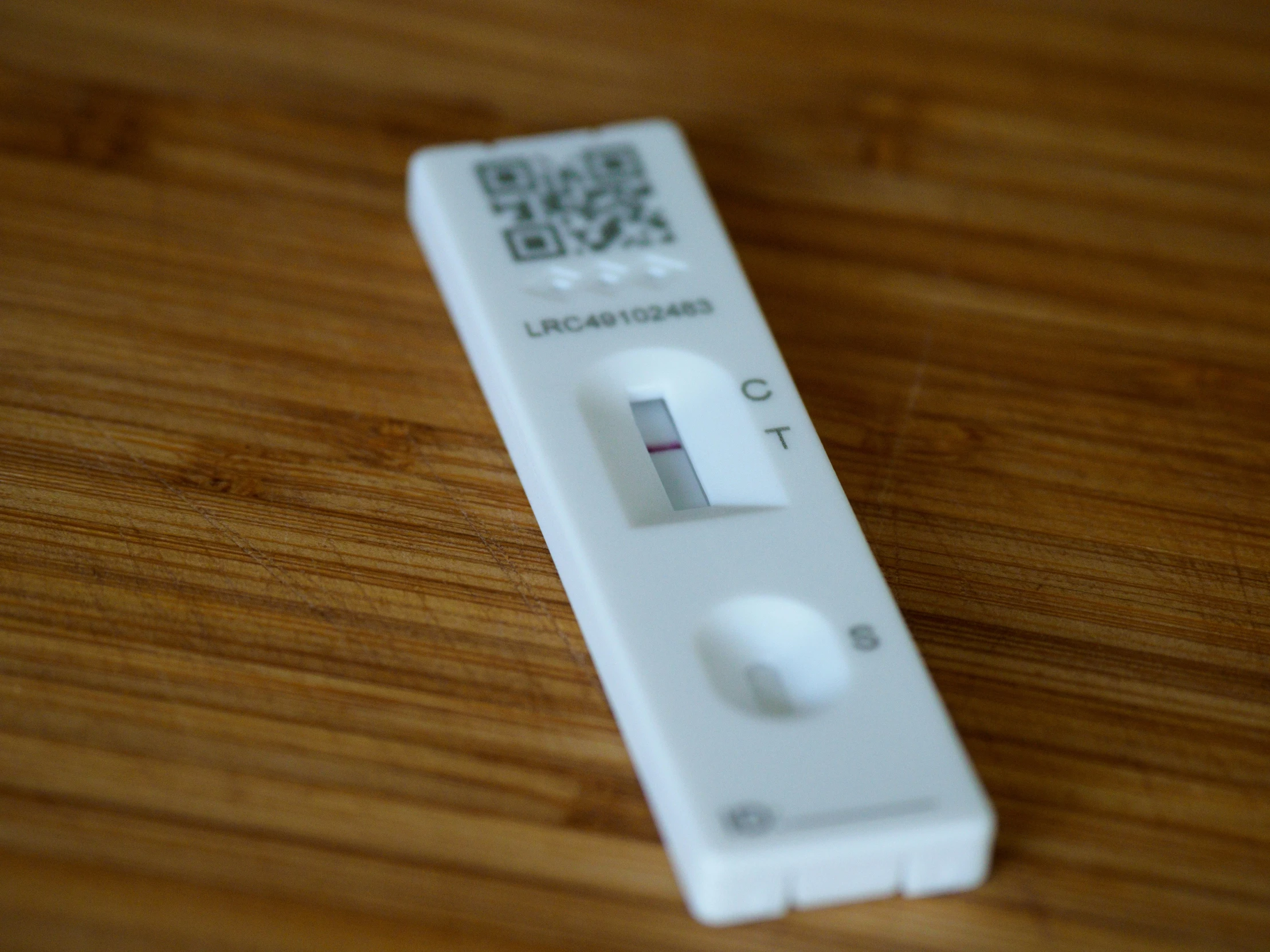 a wii remote control lying on a wooden surface