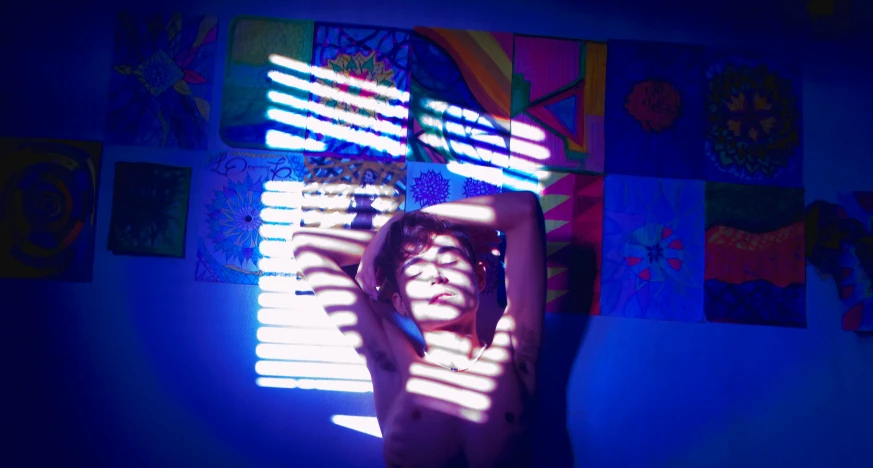 a woman posing in front of colorful art with her hands behind her head