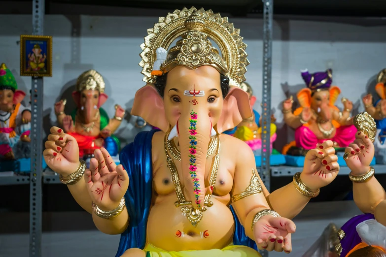 the statue of an elephant in the shop is dressed in various colors