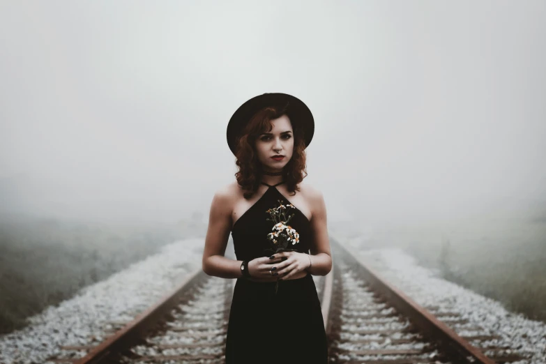 a woman standing on train tracks in the fog