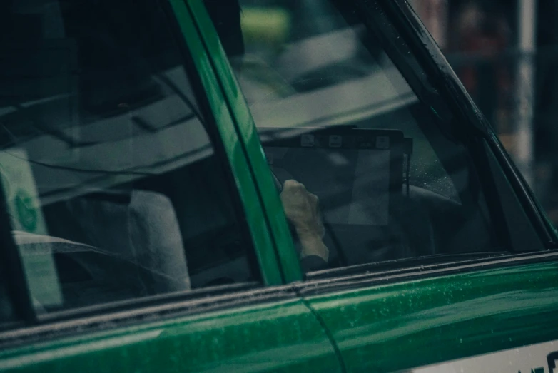 someone holding up a book inside of a green car