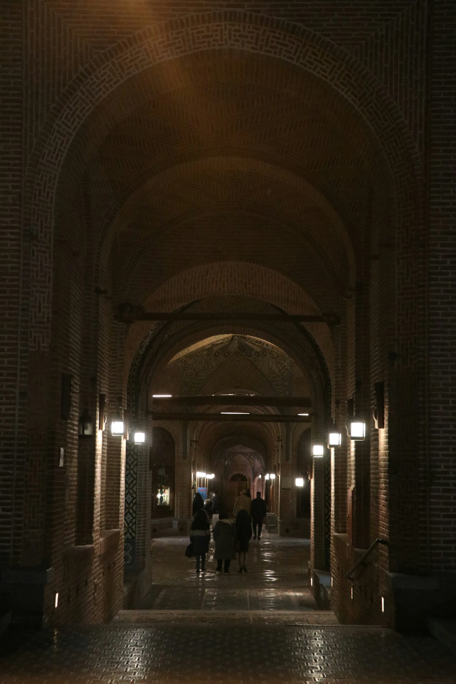 people walking through the middle of a long hallway at night