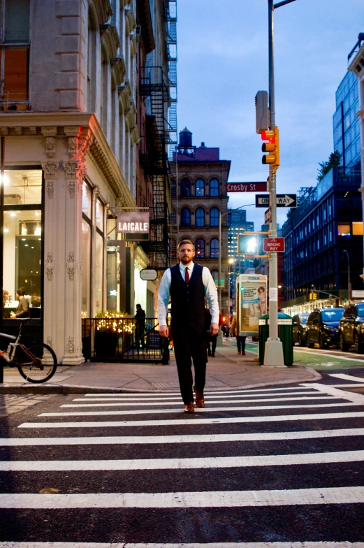 a man crosses the street as another man in a suit walks