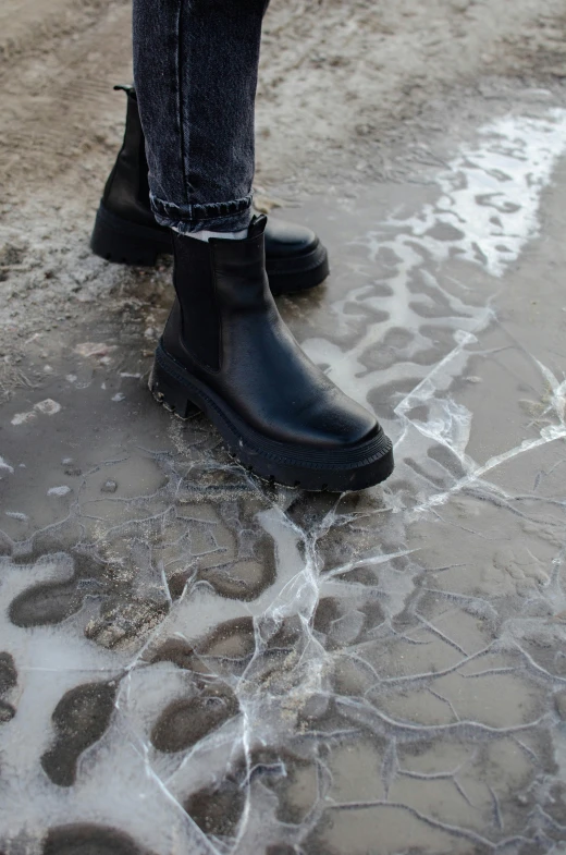 a pair of black boots are standing next to an icy dle