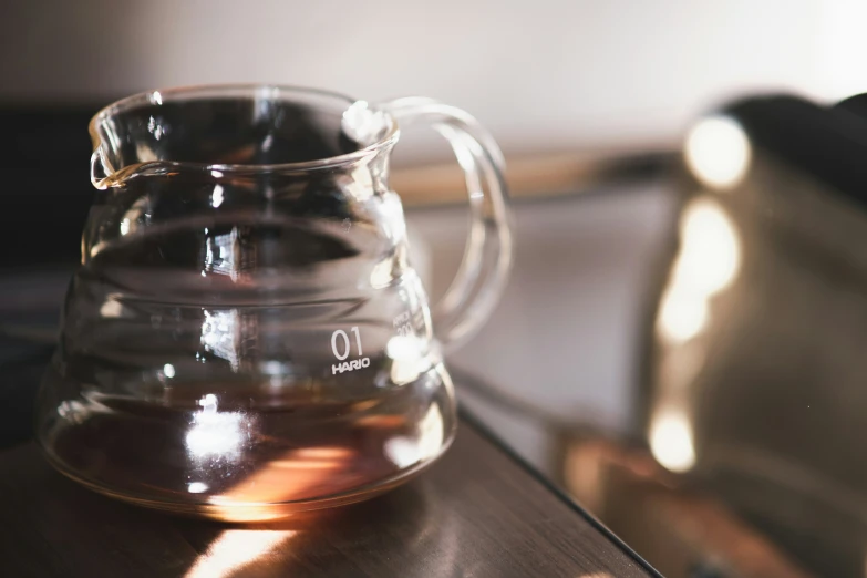 a clear pitcher is on a table with its reflection