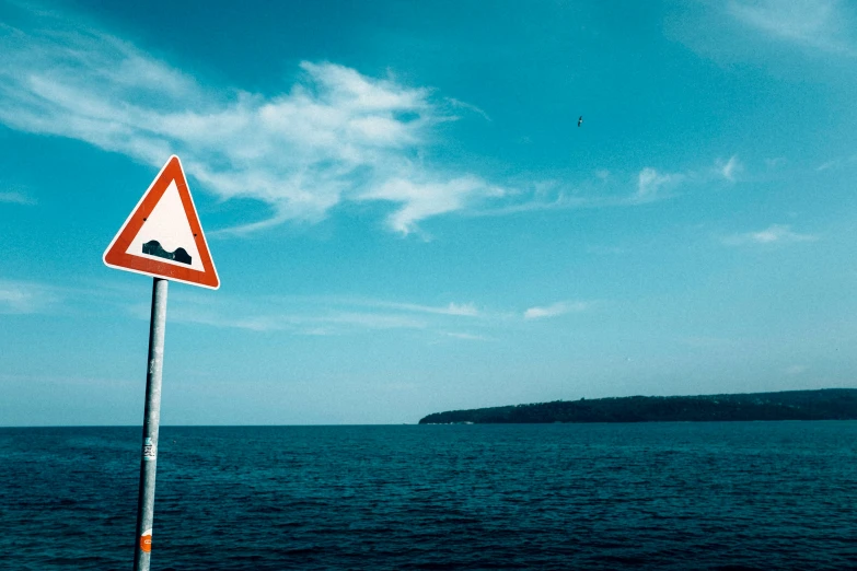 an image of the ocean that has a warning sign on it