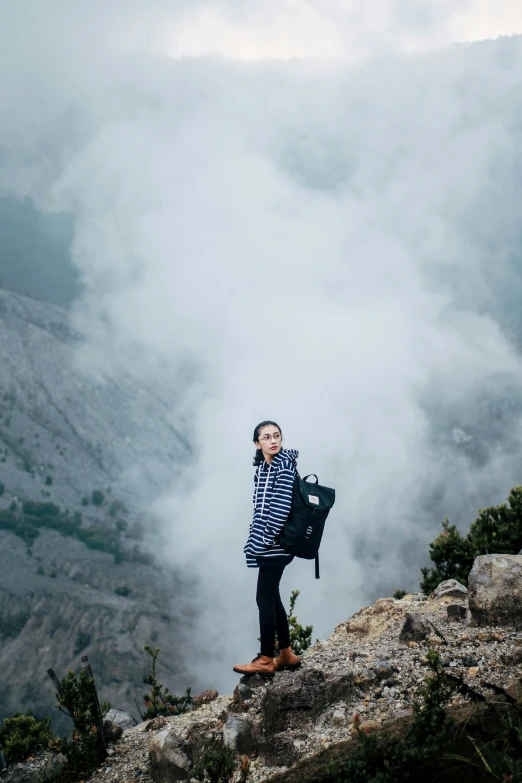 a person standing on top of a mountain covered in smoke