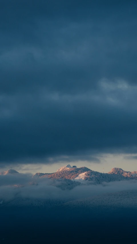 the mountains are covered in clouds beneath a dark sky