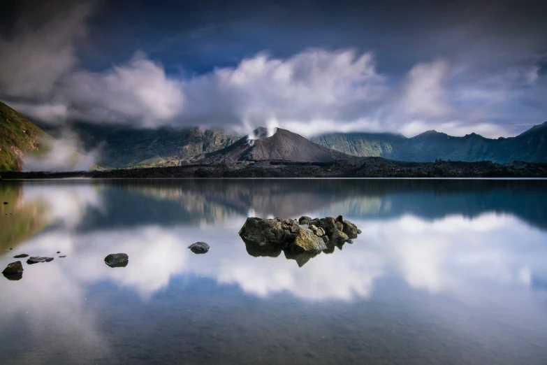 rock formations are reflected in the still water on a cloudy day