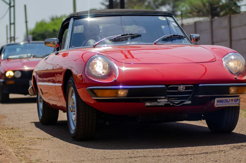 an old red sport car next to another red one