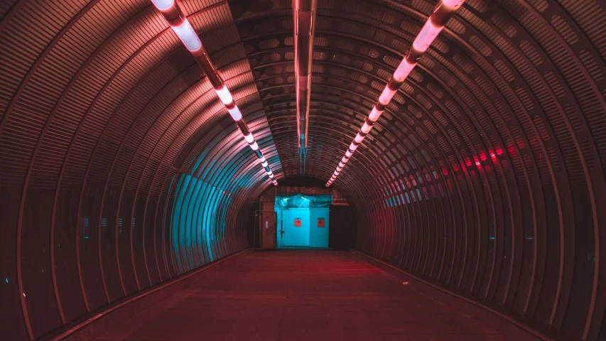 an illuminated tunnel at the end of a hallway