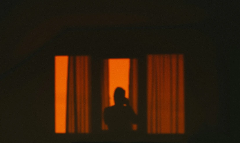 a man is standing in front of a window with curtains