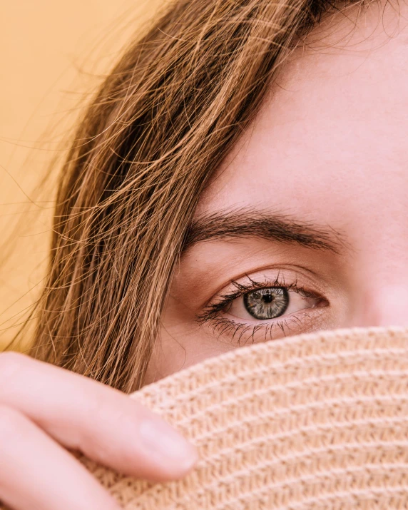 a woman is covering her eyes behind her scarf