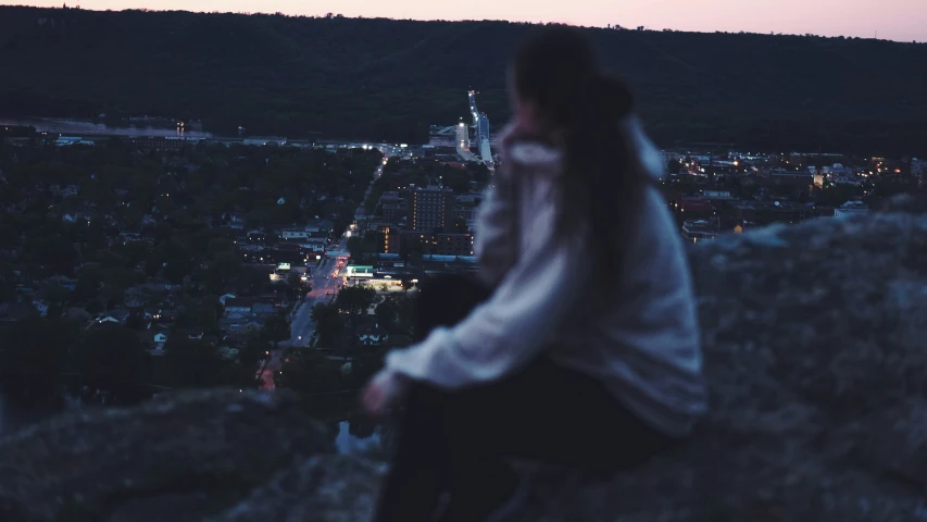 the girl is sitting on top of the mountain