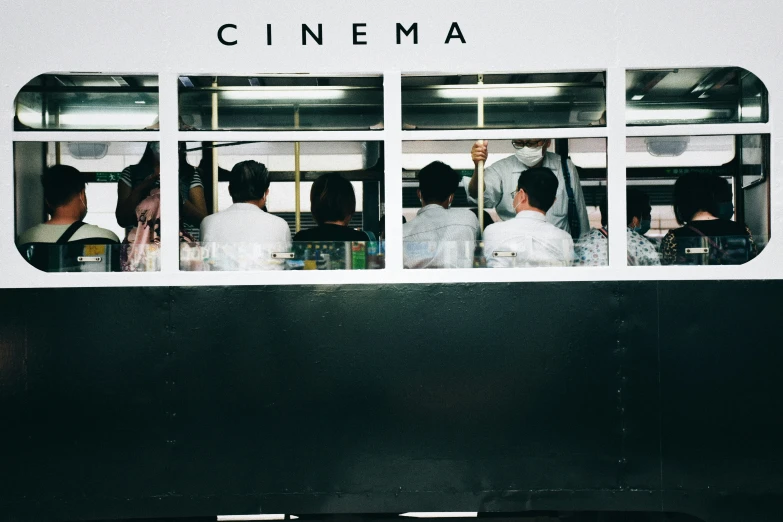 some people standing around a train door with the words cinema written on the side