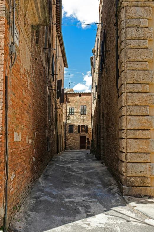 an empty narrow stone alley with buildings on either side