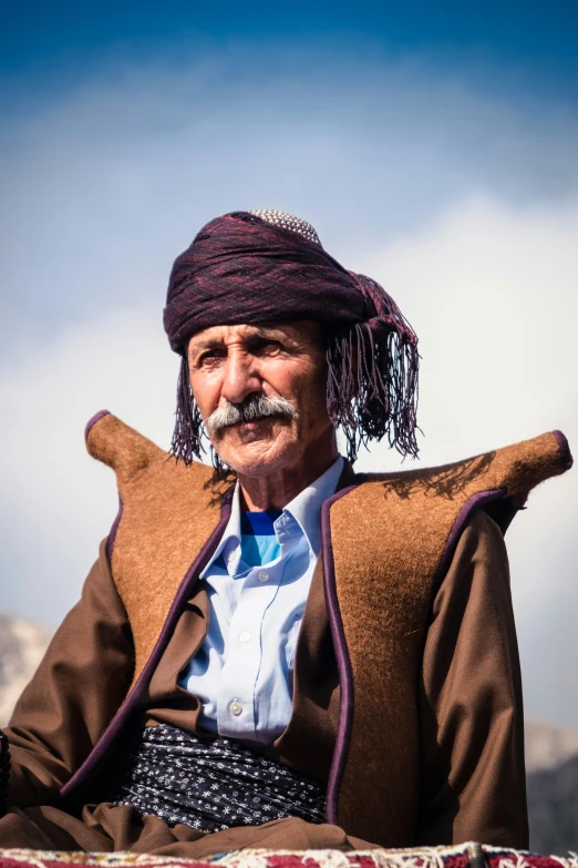 a man with a mustache sits with an old jacket on