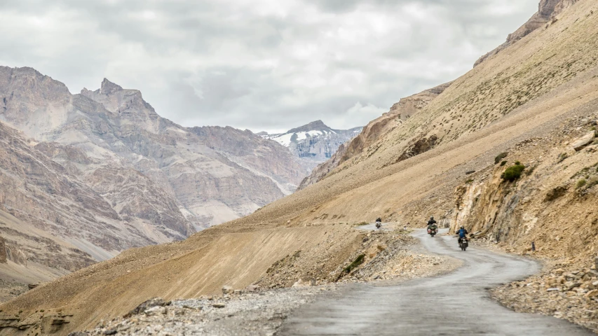 some bikers traveling down a narrow road