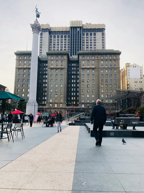 a man walks down a walkway next to a statue