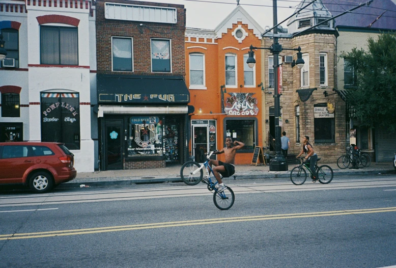 some people riding bikes down a street next to buildings