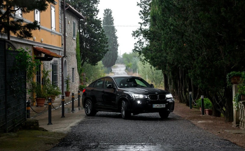 a black car parked on the side of a road in a rural setting