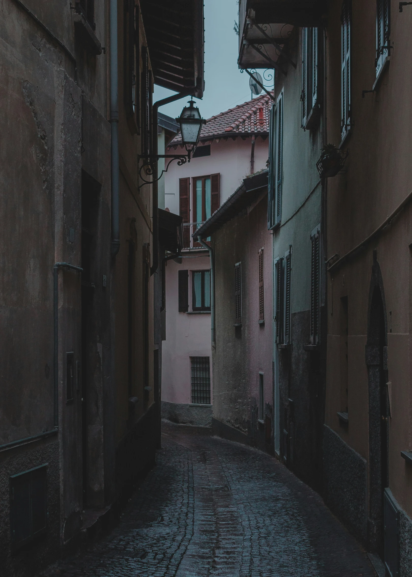 an alleyway between two old buildings with one car parked in the street