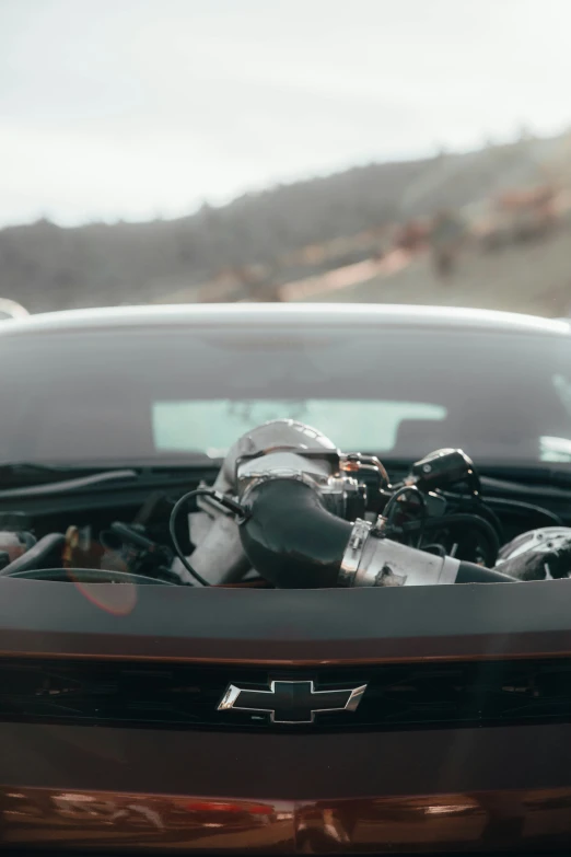 the engine compartment of a car, with a view of a mountain in the background