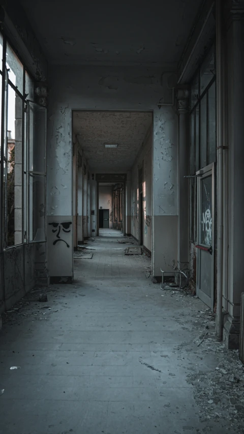 a dark hallway with lots of windows and graffiti on the walls