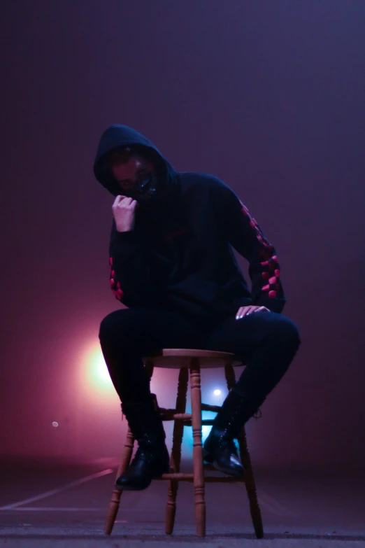 a person sitting on a stool with their hands near their face