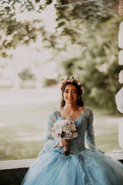 a woman in blue and white gown sitting in front of trees