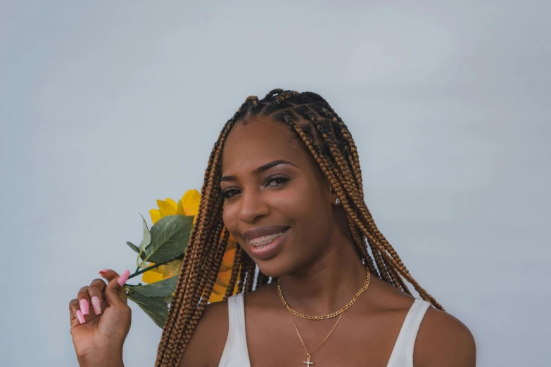 a young woman is holding flowers and wearing a yellow hat