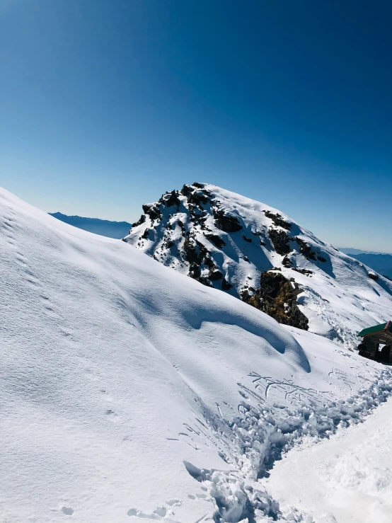 snowboarder with blue jacket on top of a snowy mountain