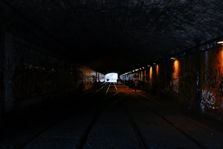 a dark tunnel with railroad tracks and lights