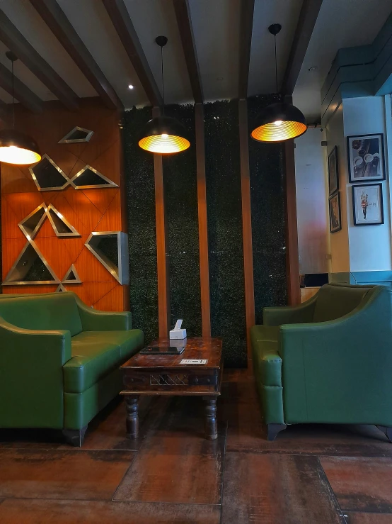 green chairs in the lobby are near a wall with wood paneling