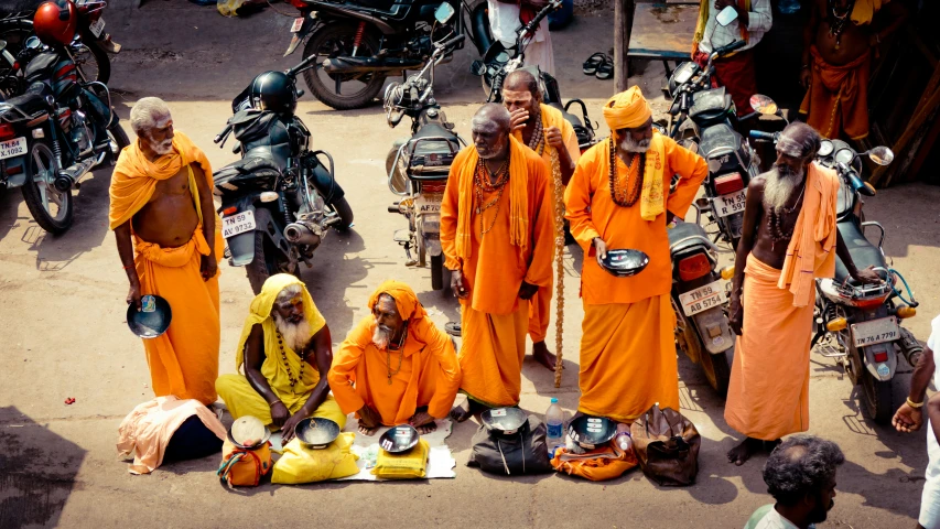 several people in orange outfits stand in front of motorcycles