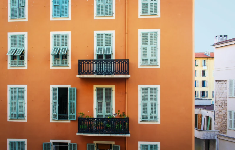 a multistory orange building with shutters and balconies on the windows