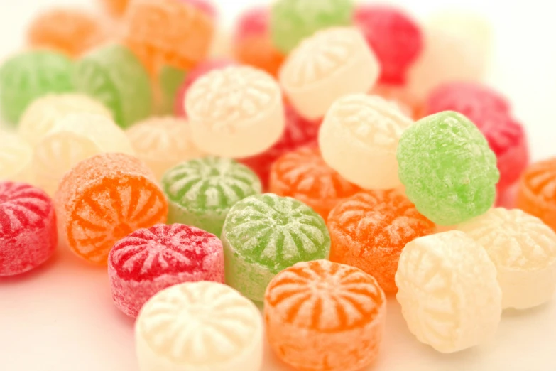 many different colored candies on a white table