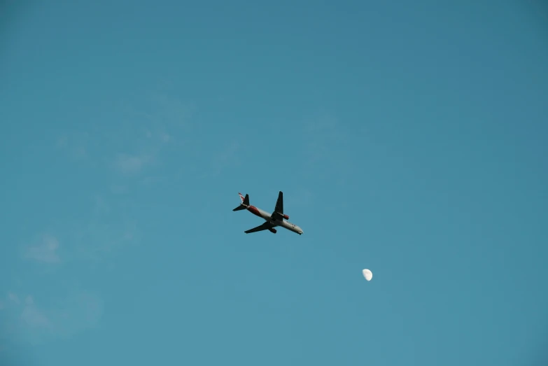 an airplane flying by with moon in the background