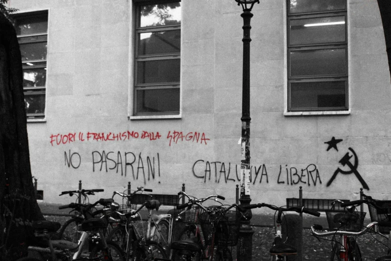 a black and white picture shows bikes parked near a building with graffiti