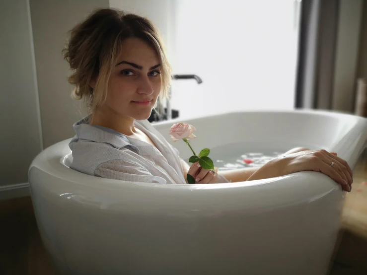 a woman sitting in a bathtub holding a flower