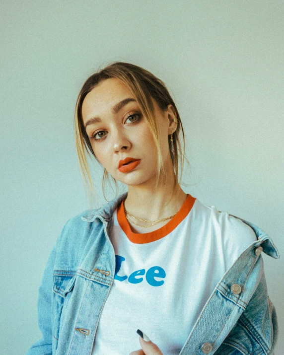 young lady wearing a denim jacket and t - shirt holding a pen