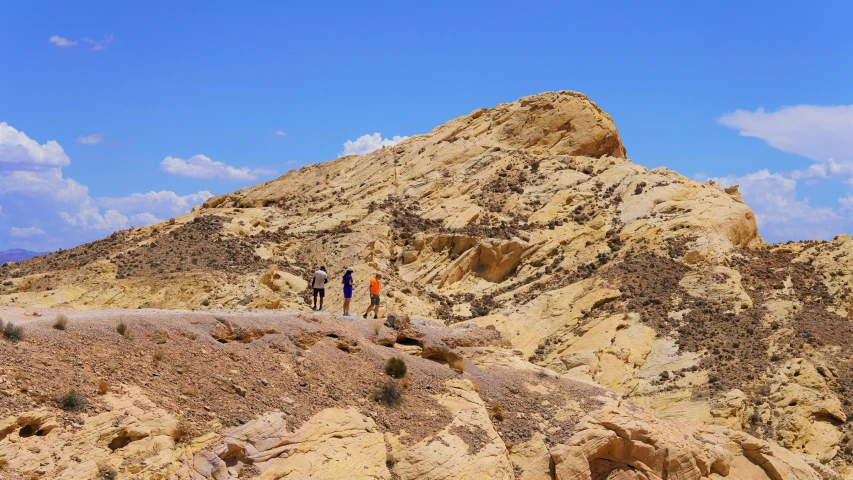 some people are hiking up a sandy hill