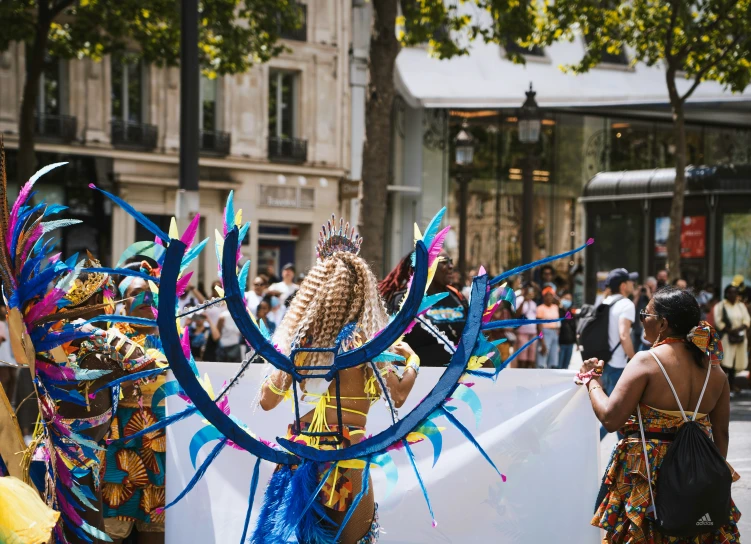 women in brightly colored costumes holding a giant white banner