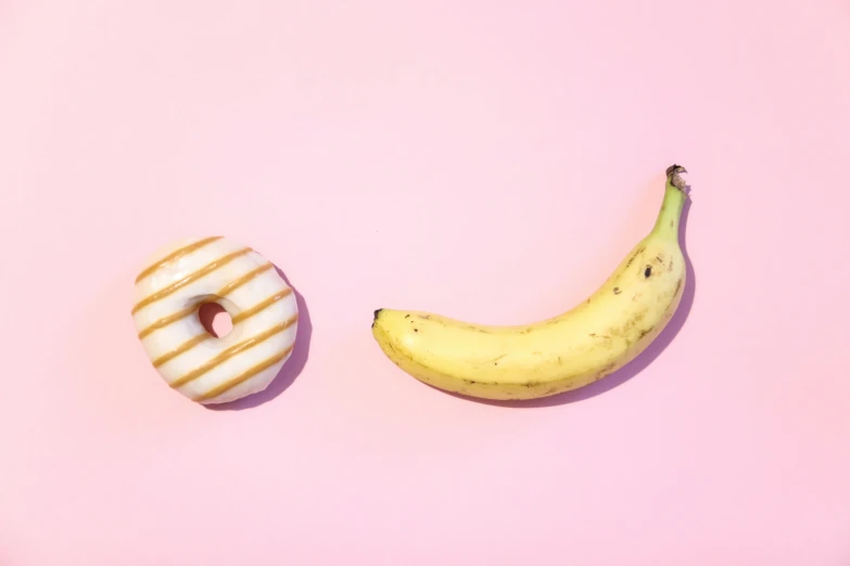 an apple and banana cut in half, displayed on a pink surface