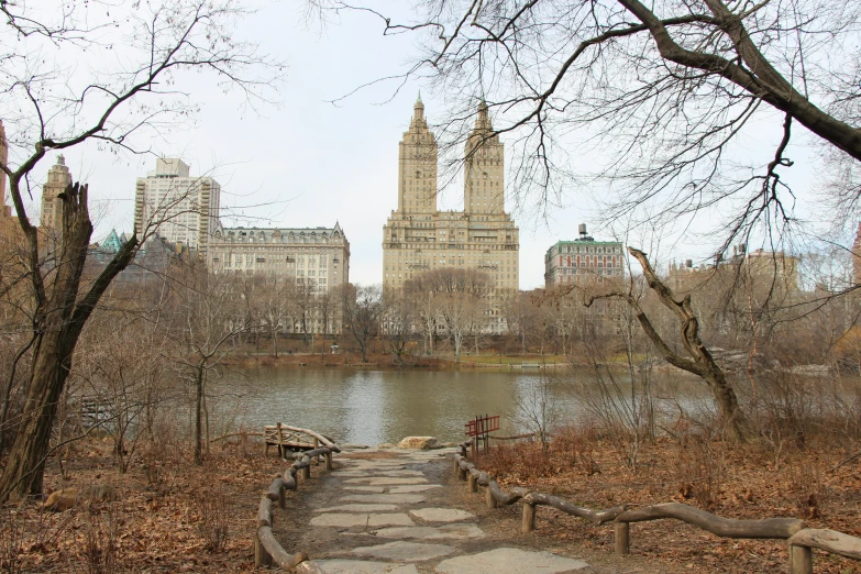 the path to a park overlooks a river, buildings and skyscrs