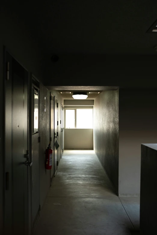 a hallway leading to the bright light in a school or apartment building