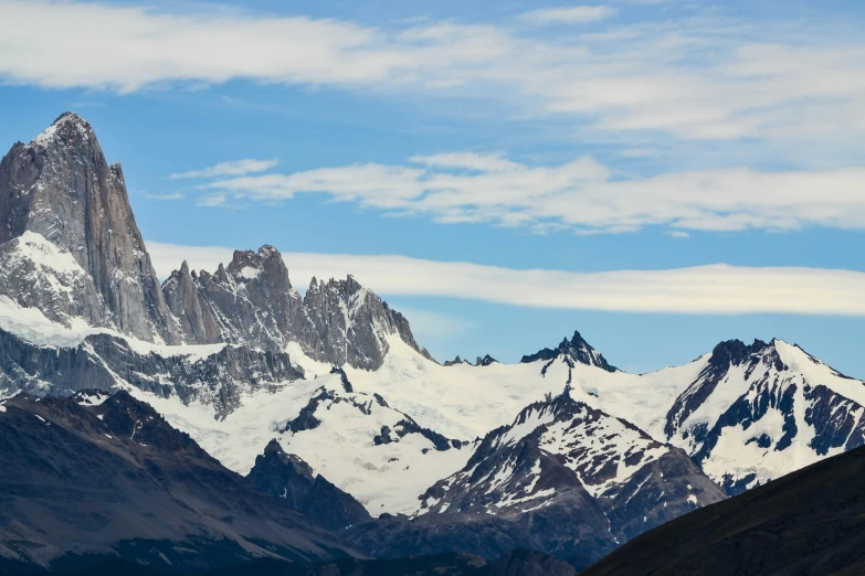 some snow capped mountains are under a blue sky